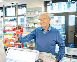 Hình ảnh về smiling pharmacist handing medication to a patient in a brightly lit pharmacy